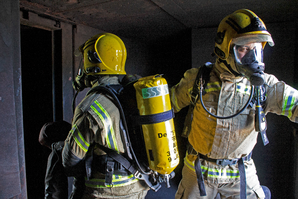 2 firefighters wearing new drager breathing apparatus kit entering smoke damaged room